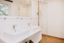 Bathroom in the holiday apartment Appartements Prielau by we rent apartments, with a shower, double sink, and hairdryer.