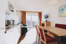 Dining room in the holiday apartment Apartments Haus Altenberger by we rent. Dining table, kitchen, living room, and balcony.
